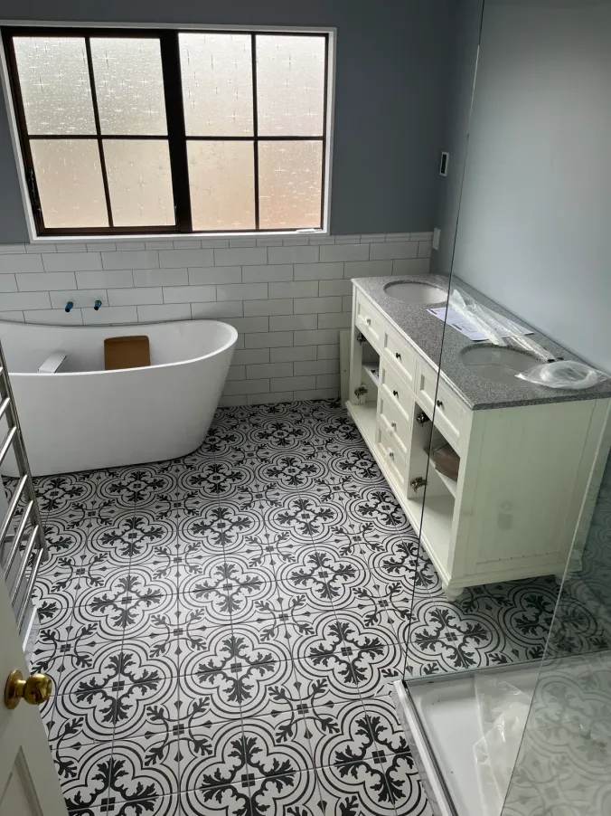 Renovated bathroom with patterned floor tiles and timber vanity