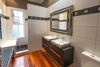 Spacious bathroom with wood floor, double sink vanity and walk-in shower