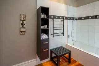 Compact bathroom with corner bathtub, shower enclosure and storage tower