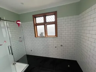Bathroom renovation in progress with white subway tiles and mint green walls