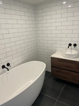 Spa-style bathroom with white soaking tub and black modern fixtures