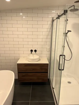 Modern shower with white subway tiles, black fixtures and vessel sink