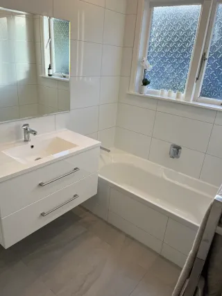 White bathroom vanity with large mirror and patterned window curtain