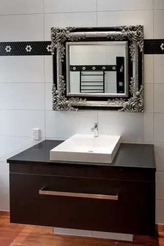 Luxury bathroom vanity with black cabinetry and decorative framed mirror